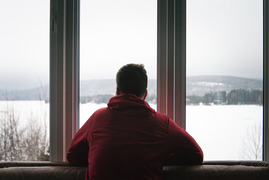 Sad man looking out the window during a foggy winter day
