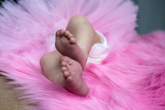 cute newborn baby tiny soft feet on pink blanket, infant baby girl in diaper and fatin skirt