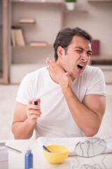 Young man shaving face at home