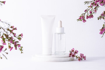 Luxury skin care products such as cream, serum, lotion, balm or mask on white background with beautiful purple flowers close up. Eco friendly herbal cosmetic banner.