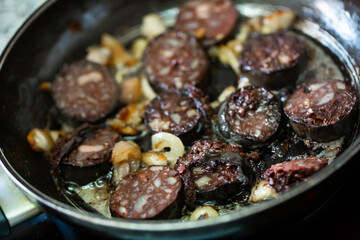 Closeup of pan with traditional Spanish morcilla blood sausage slices with rice frying with onions
