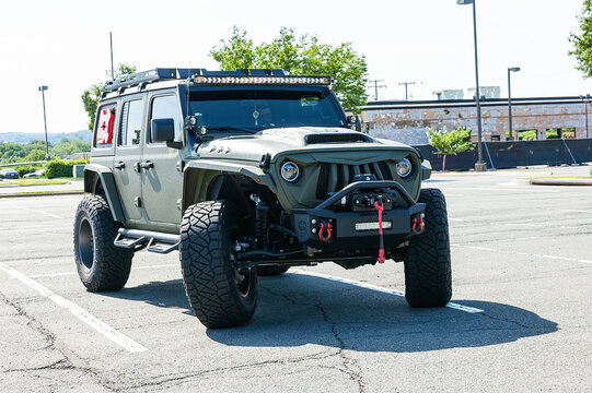 military color Jeep Wrangler is parked in a supermarket parking lot.