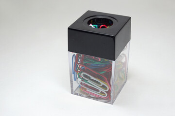 paper clip dispenser. Table plastic transparent box with magnetic square black lid many colored paperclips inside