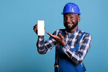 Optimistic african american contractor showing empty mobile phone screen for advertising in studio...