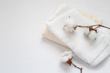 Fototapeta na wymiar flores de algodón sobre variedad de telas en tonos neutros sobre superficie blanca 