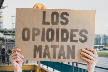 The phrase " Opioids kill " on a banner in men's hands is isolated on a white background. Medicine supply. Deadly drugs. Death. Treatment. Pharmacy. Dangerous. Drug addiction