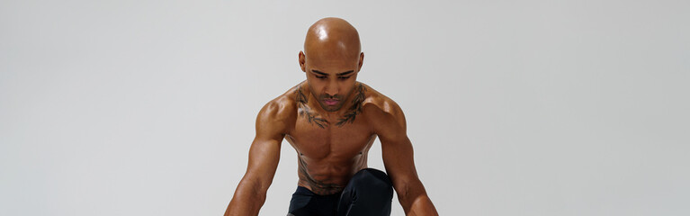 Sportsman with naked torso is warming up before workout on white studio background