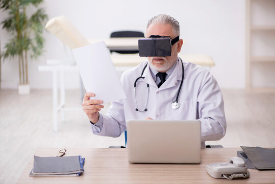 Old male doctor wearing virtual glasses in the clinic
