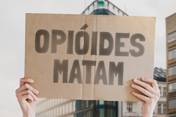 The phrase " Opioids kill " on a banner in men's hands is isolated on a white background. Medicine supply. Deadly drugs. Death. Treatment. Pharmacy. Dangerous. Drug addiction