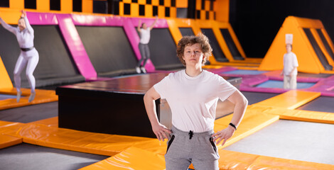 Portrait of joyful young teenager in sport clothes enjoying weekend time on trampolines in...