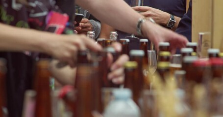 lots of bottles of beer or cider, at the festival with lots of people. a fun, summer event related to the celebration of the event. hands and opening bottles. 