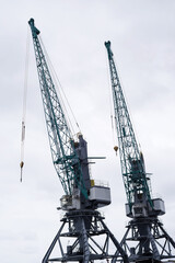Two cranes in a seaport against a cloudy sky