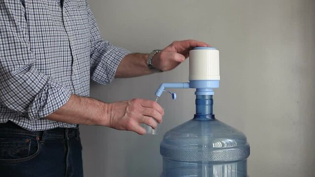 A man drinks imported bottled drinking water. A flask with artesian clean water in the office, at work.