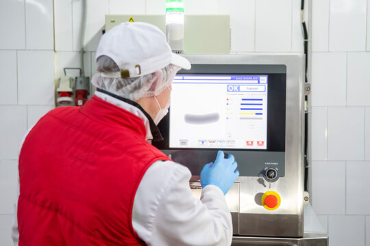 A man are working in sausage factory and he shows how works scan machine  "x ray" of them factory. Meat factory introduced boiled sausage