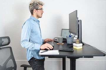 Businessman standing up while working at the office with modern standing desk