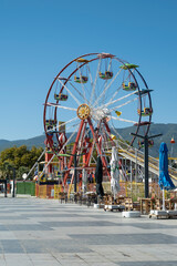Amusement park and a colorful Ferris wheel in the tourism city, fun summer fair. 
