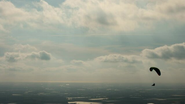 Two paragliders move peacefully and slowly in the cloudy sky. The sport of paragliding gives a feeling of tranquility, peace, strength and freedom in the open air