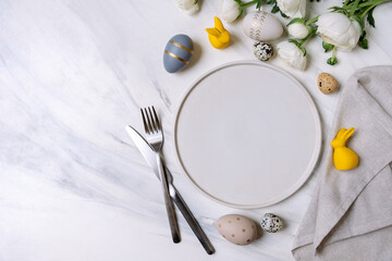 Easter table setting with white plate and decorations, Easter food background. Flat lay.