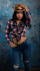 Latina wearing flannel shirt with blue jeans and boots wearing straw cowboy hat