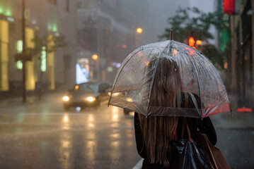 Woman holding an umbrella on a rainy night in the city of Montreal, Canada, cinematic.