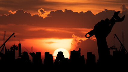 Silhouette with holding a wrench, building, construction on sunset background.