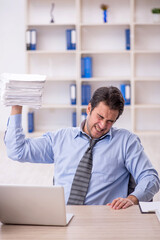 Naklejka premium Young male employee and too much work at workplace