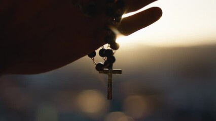 Hands clasp rosary at sunset - Powered by Adobe