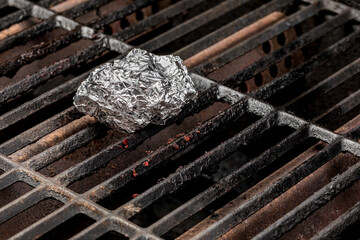 Cleaning burnt food on dirty barbecue grill grates with aluminum foil. Barbeque grilling, cleaning...