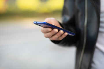 Unrecognizable man holding mobile phone in hand, blurred background