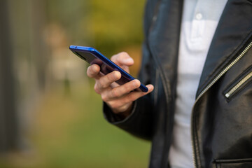 Closeup shot of an unrecognizable man holding mobile phone in hand, blurred background
