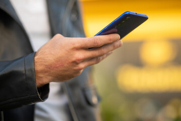 Unrecognizable man holding mobile phone in hand, blurred background