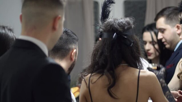 Happy young people on a vintage Great Gatsby party dressed in retro 20s fashion, cheers and drinking alcohol.