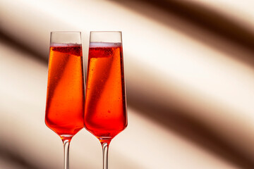 Rossini summer alcoholic cocktail drink with sparkling wine or prosecco, strawberry puree and ice in champagne glasses. Beige pink vanilla background, hard light, shadow pattern