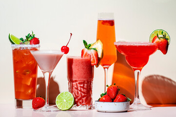 Summer strawberry alcoholic cocktails, mocktails, smoothies and shakes with fruits and berries in glasses. Refreshing cold drinks. Beige pink vanilla background, hard light, shadow pattern