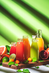 Summer drinks. Citrus fruit juices, fresh and smoothies, food background. Mix of different whole and cut fruits: orange, grapefruit, lime, tangerine with leaves and bottles with beverages