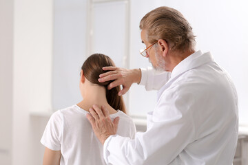 Professional orthopedist examining patient's neck in clinic