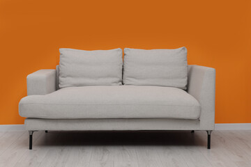 Comfortable sofa near bright orange wall indoors