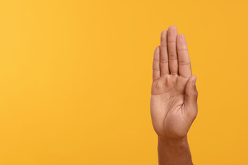 Man giving high five on yellow background, closeup of hand. Space for text