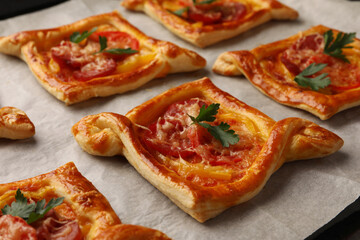 Fresh delicious puff pastry with tasty filling on baking sheet, closeup
