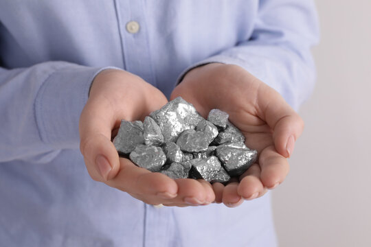 Woman with silver nuggets on light grey background, closeup