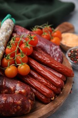 Different types of tasty sausages and ingredients on light grey table, closeup