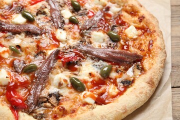 Tasty pizza with anchovies and olives on wooden table, closeup