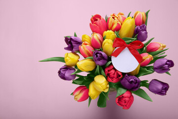 Bouquet of beautiful colorful tulips with blank card on beige background, top view and space for...