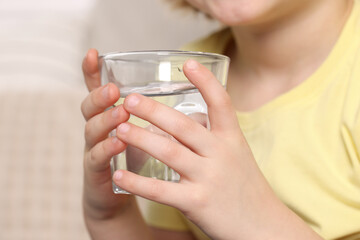 Little boy holding glass of fresh water, closeup