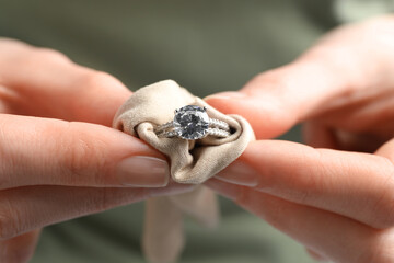 Jeweler cleaning diamond ring with microfiber cloth, closeup