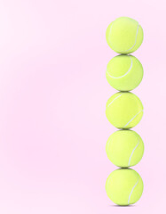 Stack of tennis balls on pale pink background. Space for text