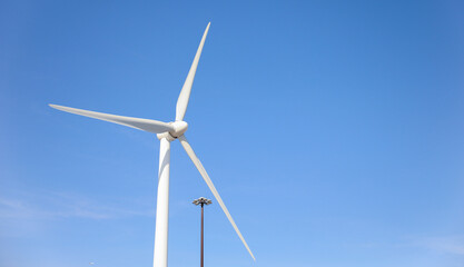wind turbine standing tall against a clear blue sky, symbolizing sustainability, renewable energy, and the use of alternative energy resources in industry