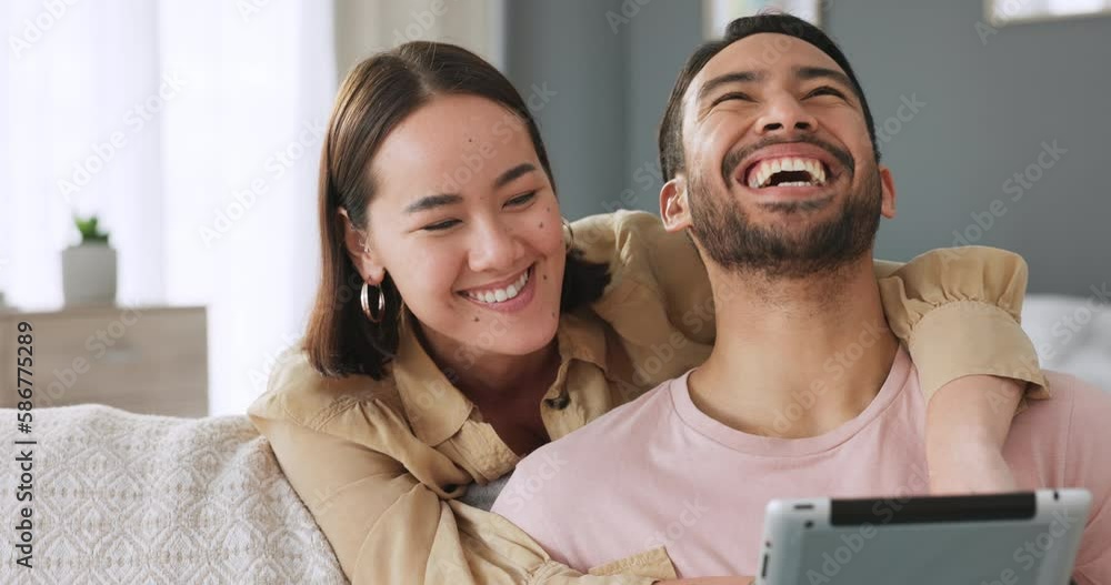 Wall mural Asian young couple with tablet on social media app watch online web or internet fun meme video on living room sofa. Happy Japanese man and woman in dating relationship together laugh in happiness