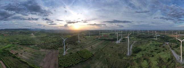 Panoramic view of a windmills with a gray sky and green forest in evening light, Renewable energy, Environmental protection.