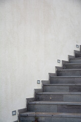The staircase on the white wall of the building in the park, the gray stone staircase on the white...
